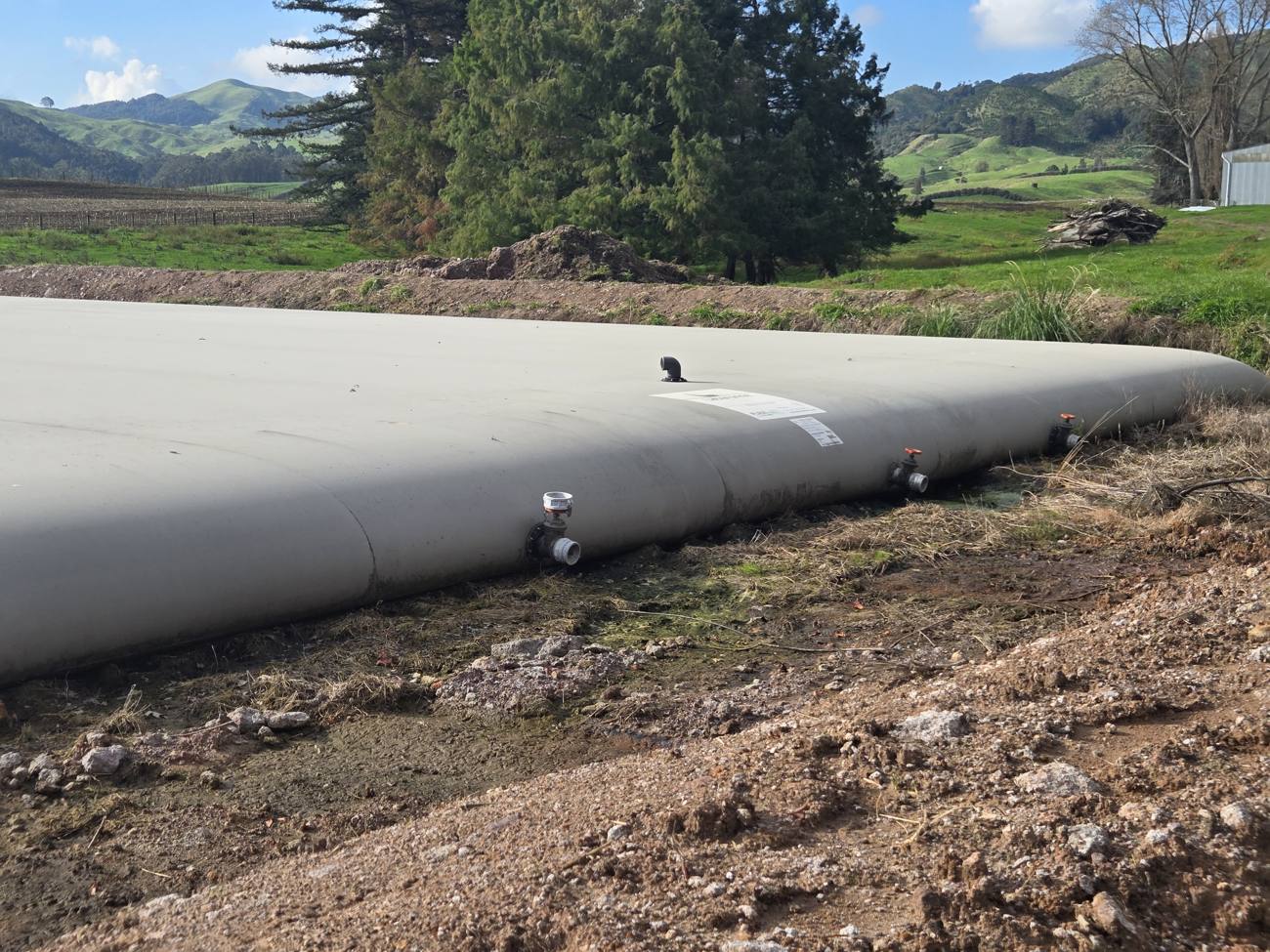 Covered Kliptank infrastructure beside trees and worked land