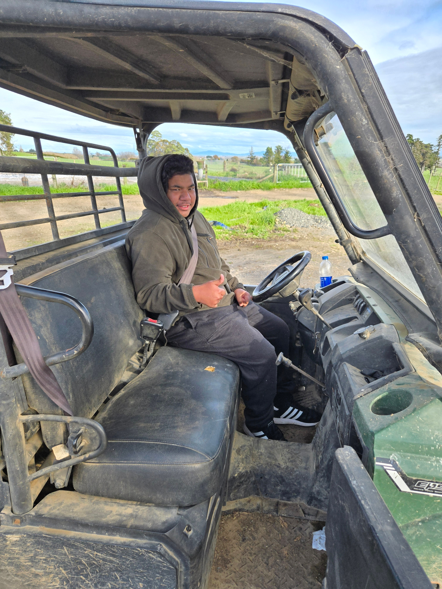 Josh giving a thumbs up from the driver's seat of a farm ATV