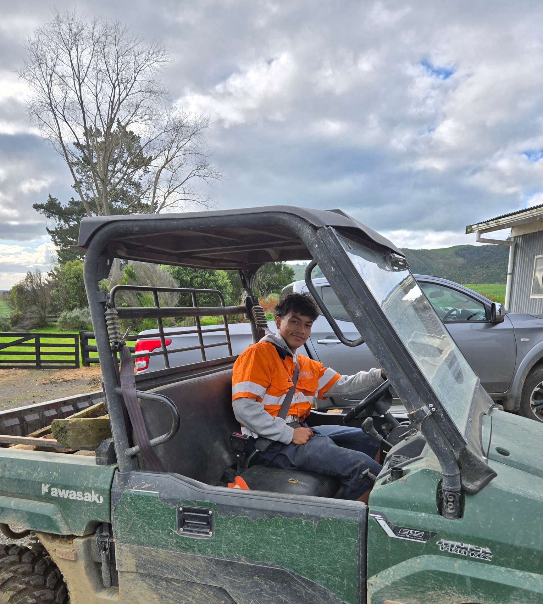 Shades in hi-vis at the wheel of a Kawasaki side-by-side on the farm